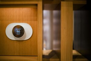 A homeowner installing a smart contact sensor on a wooden door frame for home automation security